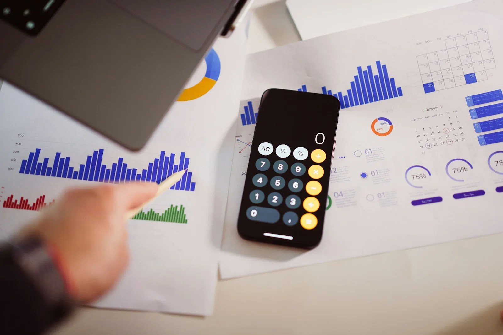 A calculator on a table next to a laptop