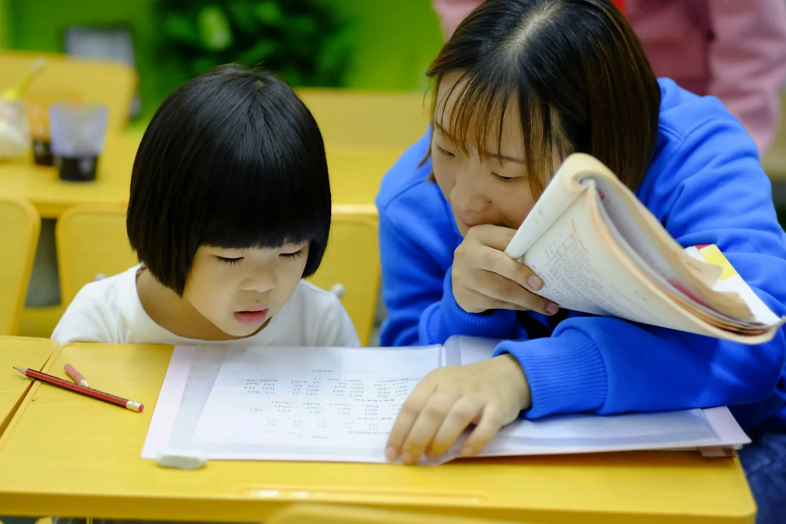 Woman teaching a young girl at a table