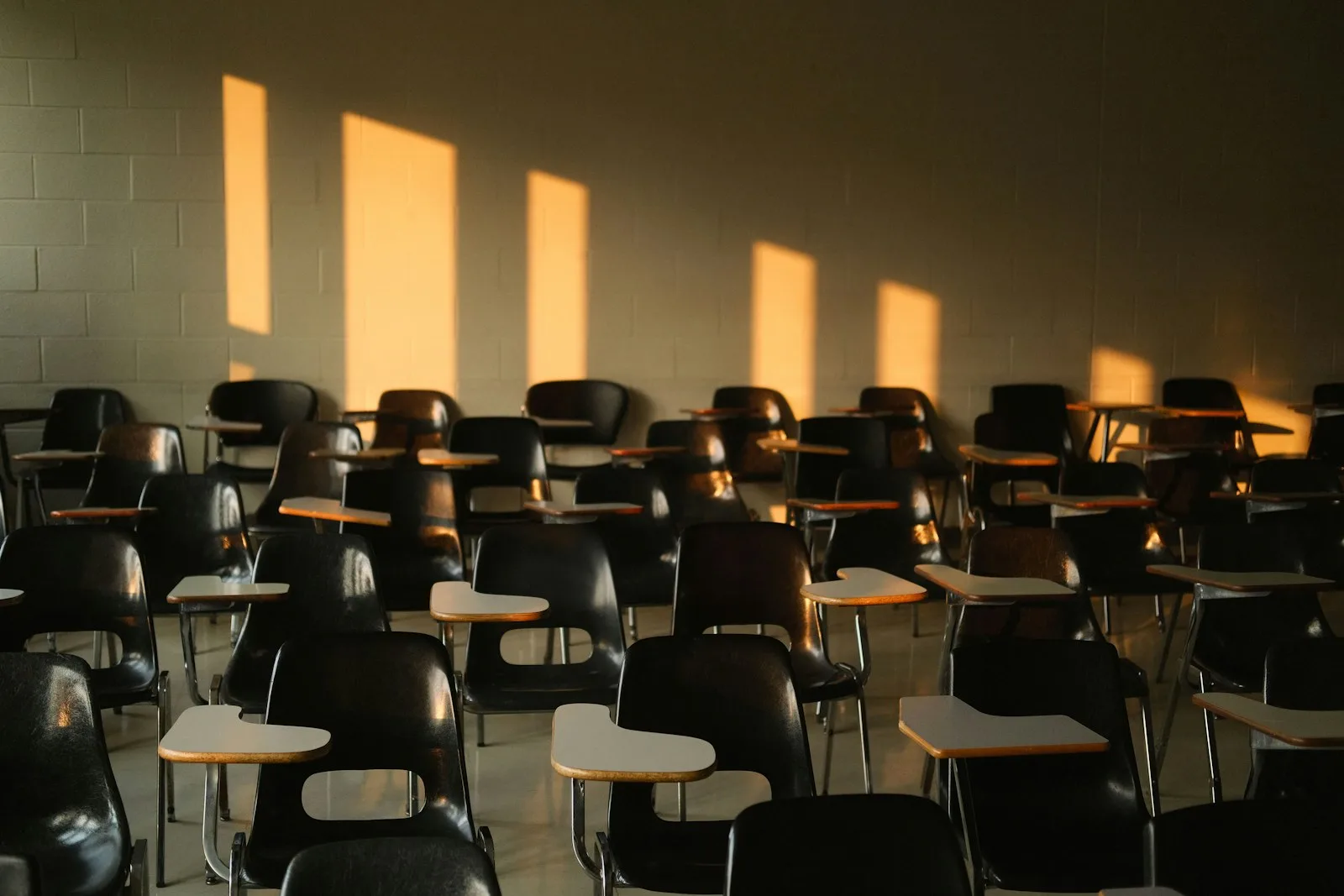 Empty classroom with sunlight casting shadows across the desks