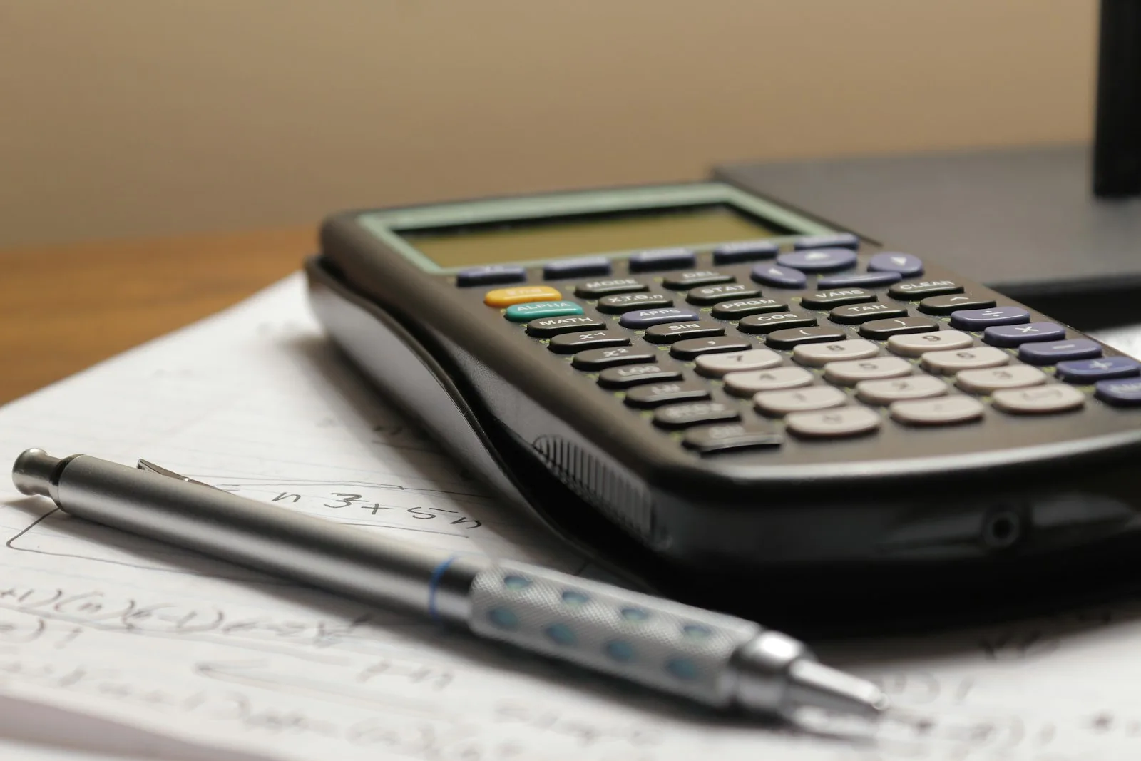 A calculator and a pen on a sheet of paper