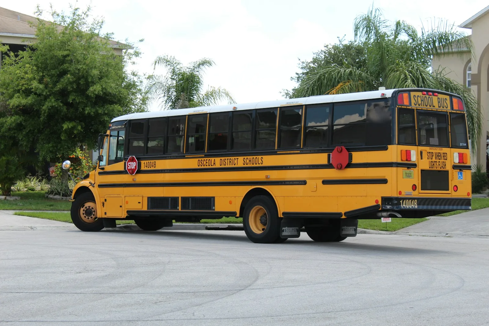 Yellow school bus parked outside a school on a sunny day